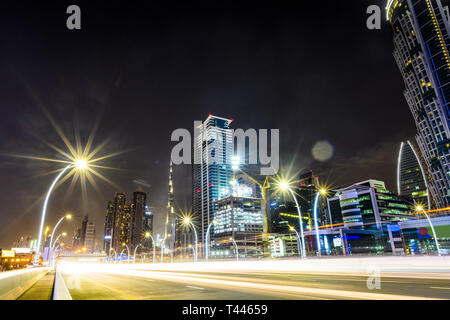 Splendida vista dell'illuminato skyline di Dubai di notte con il magnifico Burj Khalifa in background e una strada molto trafficata con percorsi di luce. Foto Stock