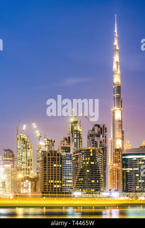Splendida vista dell'illuminato skyline di Dubai durante il tramonto con il magnifico Burj Khalifa e molti altri edifici e grattacieli. Foto Stock