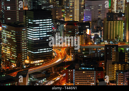 Vista aerea di una autostrada che attraversano un edificio per uffici nel quartiere Umeda di notte. Osaka, Giappone. Foto Stock