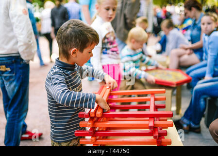 La Russia, città Mosca - 6 Settembre 2014: Il ragazzo raccoglie il progettista di bastoni di legno. Gli amanti del bambino raccoglie i dettagli in legno del designer Foto Stock