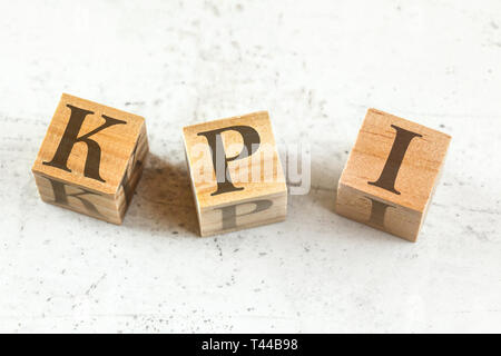 Tre cubi di legno con lettere KPI sta per indicatore di prestazioni chiave sul pannello bianco. Foto Stock