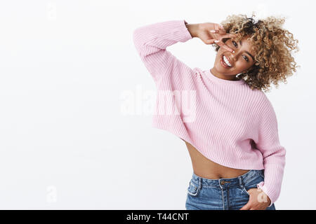 Oh yeah, ragazza gode di vacanze invernali. Carismatico e spensierata silly carino americano africano con la donna bionda acconciatura afro gesticolando e testa tiltante showi Foto Stock