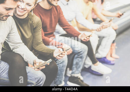 Gruppo di amici utilizzando insieme il loro cellulare smart phone mentre è seduto in metropolitana - Giovani navigare sui social network sul telefono Foto Stock