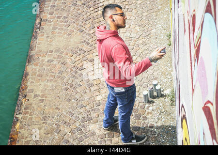 Street Graffiti artist pittura con un colore spray può un graffito murale sulla parete - Urban, lifestyle, arte di strada Nozione Foto Stock