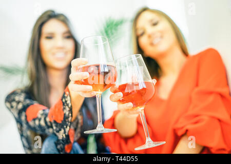 Giovani donne tostatura di bicchieri di vino rosato nella loro casa - Happy sorelle godendo il loro tempo insieme a bere cocktail e divertirsi Foto Stock