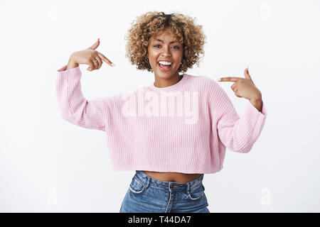 Hey è me che avete bisogno. Ritratto di felice ed entusiasta di buona cercando di carnagione scura ragazza con piercing e biondi capelli afro sorridente suggestin con gioia Foto Stock