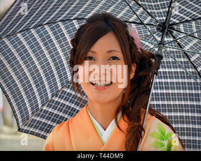 Bella, giovane donna giapponese pone sotto il suo ombrello in un giorno di pioggia. Foto Stock