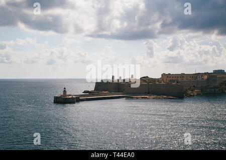 Vista del Grand Harbour di entrata e antico borgo medievale Ricasoli Oriente frangionde con faro rosso e Fort Ricasoli visto da La Valletta, Malta Foto Stock