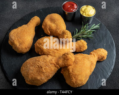 Fritti croccanti le cosce di pollo impanato colore oro su sfondo nero Foto Stock