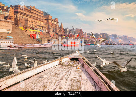 Varanasi antica India città architettura come visto da una barca sul fiume Gange con vista di uccelli migratori con moody Cielo di tramonto Foto Stock