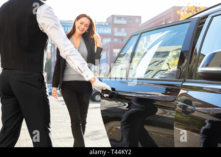 Apertura con autista con auto privata porta per imprenditrice Foto Stock