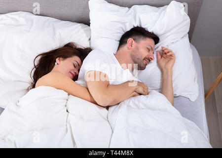 Giovani amare giovane che dorme sul letto con coltre bianca Foto Stock