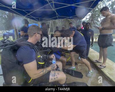 SANTA RITA, Guam (feb. 20, 2019) Navy Diver 1a classe Ryan Guenther, centro, assegnato al mobile di immersioni subacquee e di unità di soccorso (MDSU) 1, aiuta un dello Sri Lanka navy diver don la sua marcia di immersione durante il corso di formazione in preparazione per esercitare la cooperazione a galla la prontezza e la formazione (Carati) Sri Lanka 19. Questo pre-allenamento è stato progettato per familiarizzare il di Sri Lanka team con attrezzature e pratiche che portano fino a caso a partire da aprile. Foto Stock