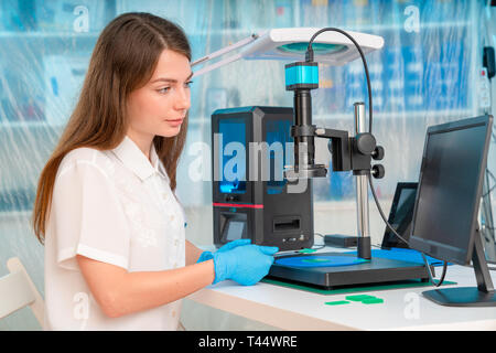 Lavoratore di sesso femminile nel controllo di resina LCD / DLP / SLA stampante 3D nel laboratorio di tecnologia Foto Stock