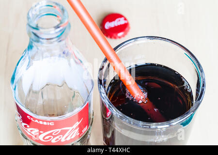 Mosca, Russia - aprile 4, 2019: bottiglia vuota di Coca Cola bevande, drink in vetro rosso con cannuccia e cappuccio usato. La coca cola (coke) carbonato Foto Stock