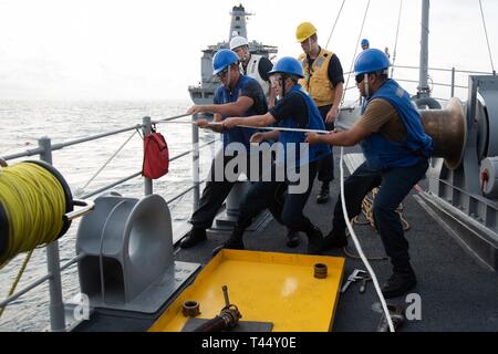 Sul mare del sud della Cina (feb. 24, 2019) marinai tirare un flessibile carburante a bordo il vendicatore classe contromisure mine nave USS Chief (MCM 14) durante un rifornimento in mare con USNS Guadalupe (T-AO 200). Chief, parte della miniera contromisura Squadron 7, è operativo nell'Indo-Pacifico regione per migliorare l'interoperabilità con i partner e servire come una pronta risposta a piattaforma per operazioni di emergenza. Foto Stock