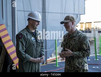 NEWPORT NEWS, Va. (feb. 25, 2019) Capt. John J. Cummings, USS Gerald Ford (CVN 78) comandante, parla con il cap. Tom Moninger, commander, Destroyer Squadron 22, durante un tour di Ford di evidenziazione delle sue funzionalità. Ford è attualmente in fase di post-shakedown disponibilità presso Huntington Ingalls Industries-Newport News la costruzione navale. Foto Stock