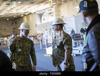 NEWPORT NEWS, Va. (feb. 25, 2019) Capt. Tom Moninger, commander, Destroyer Squadron 22, sinistra, parla con Lt. La Cmdr. Roger Horne, USS Gerald Ford (CVN 78) 3-M officer, durante un tour di Ford di evidenziazione delle sue funzionalità. Ford è attualmente in fase di post-shakedown disponibilità presso Huntington Ingalls Industries-Newport News la costruzione navale. Foto Stock