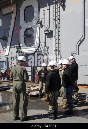 NEWPORT NEWS, Va. (feb. 25, 2019) della Cmdr. Mehdi Akacem, sinistra, USS Gerald Ford (CVN 78) air boss, mutandine membri del destroyer Squadron 22 personale, durante un tour di Ford di evidenziazione delle sue funzionalità. Ford è attualmente in fase di post shakedown disponibilità presso Huntington Ingalls Industries-Newport News la costruzione navale. Foto Stock