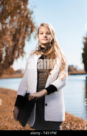 Ritratto di giovane bella ragazza adolescente. stand con laptop in natura nei pressi del lago. tonica Foto Stock