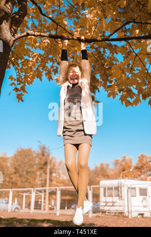 Bambino felice sorridente. adolescente gioca, si arrampica su un albero e si aggrappa a un ramo Foto Stock