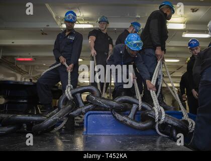 NEWPORT NEWS, Va. (feb. 27, 2019) velisti assegnati alla USS Gerald Ford (CVN 78) coperta preparare per il sollevamento di Ford in catena di ancoraggio sul wildcat. Ford è attualmente in fase di post-shakedown disponibilità presso Huntington Ingalls Industries-Newport News la costruzione navale. Foto Stock