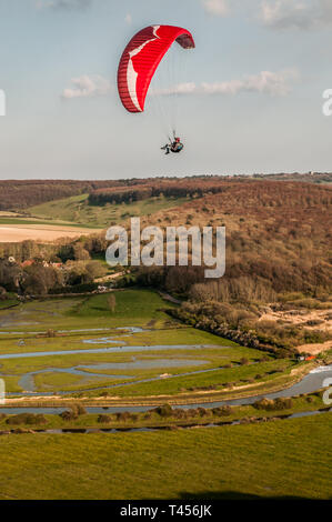 Seaford, East Sussex, Regno Unito. 13th aprile 2019. Il vento più freddo da Est porta i piloti di parapendio ad alta e Alta nel bellissimo South Downs che si affaccia sul fiume Cuckmere. Foto Stock