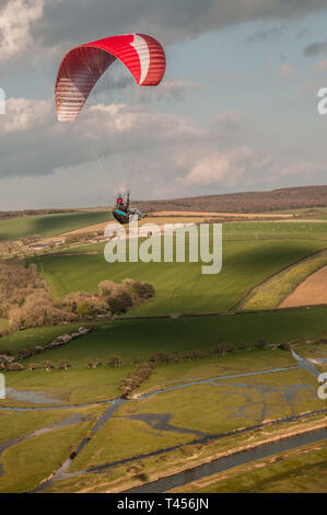 Seaford, East Sussex, Regno Unito. 13th aprile 2019. Il vento più freddo da Est porta i piloti di parapendio ad alta e Alta nel bellissimo South Downs che si affaccia sul fiume Cuckmere. Foto Stock