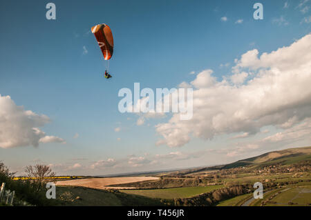 Seaford, East Sussex, Regno Unito. 13th aprile 2019. Il vento più freddo da Est porta i piloti di parapendio ad alta e Alta nel bellissimo South Downs che si affaccia sul fiume Cuckmere. Foto Stock