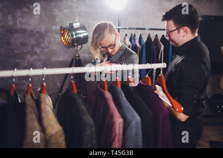 Matura sarto professionale prendendo le misure per la cucitura di adattarsi al negozio di sartoria. Uomo con nastro di misurazione occupato. Exclusive Custom made tela concetto. Foto Stock