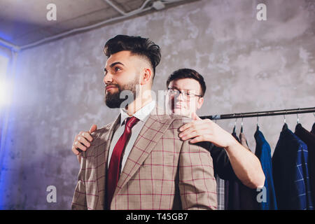 Matura sarto professionale prendendo le misure per la cucitura di adattarsi al negozio di sartoria. Uomo con nastro di misurazione occupato. Exclusive Custom made tela concetto. Foto Stock