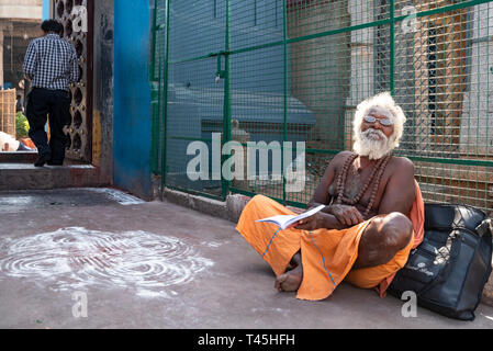 Ritratto orizzontale di un vecchio Sadhu seduto davanti alle porte del tempio Kapaleeshwarar a Chennai, India. Foto Stock