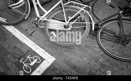 Segno con il testo si prega di non parcheggiare le biciclette qui sul pavimento con le biciclette accanto ad essa in Amsterdam Foto Stock