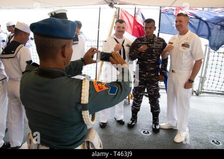 SUNDA STRAIT (1 marzo 2019) Capo Logistica specialista Timothy Henderson (destra), da Bement, Illinois, e Mineman 2a classe Trenton Robison, da Pinson, Alabama, entrambi assegnati per il Vendicatore di classe contromisure mine nave USS Chief (MCM 14), posa per una foto con un marina indonesiana (TNI-al) sailor dopo un memoriale di servizio a bordo della nave indonesiana Kri Usman Harun (359). La cerimonia si è tenuta a onorare gli americani e australiani equipaggi di USS Houston (CA 30) e HMAS Perth (D 29) che hanno perso la vita nella battaglia contro il giapponese della Marina Imperiale durante la Seconda Guerra Mondiale. Foto Stock