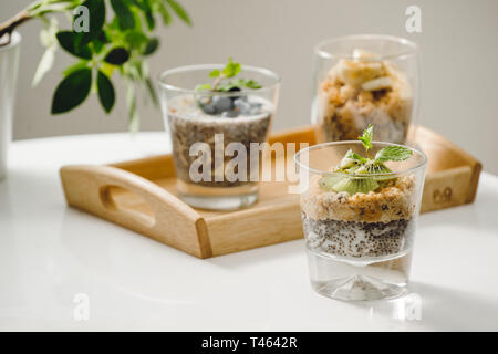 Frutti parfait di yogurt con granola e semi di chia per una sana prima colazione sul tavolo di legno Foto Stock