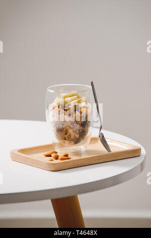 Pronto a mangiare sano una nutriente colazione - granola con mandorle e semi di Chia, banana e kiwi frutti e bacche e un vaso con latte nelle vicinanze Foto Stock