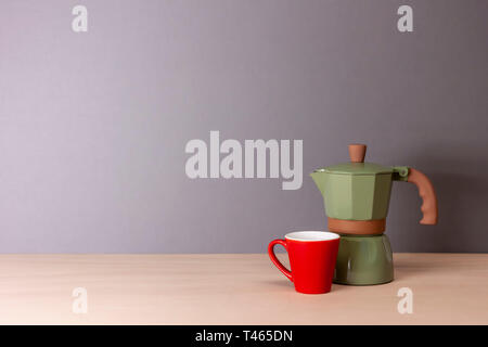 Italian coffee maker e piccola tazza su sfondo grigio Foto Stock