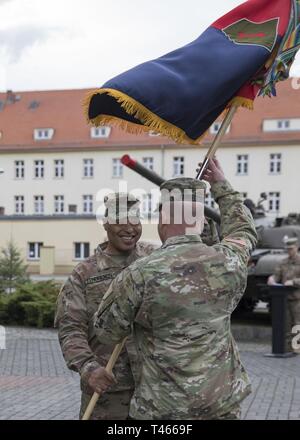 ZAGAN, Polonia - Comando Sgt. Il Mag. Quentin V. Fenderson mani la brigata di colori al Col. Charles S. Armstrong il comandante del 1 ° brigata corazzate contro la squadra, 1a divisione di fanteria, Marzo 4 2019. Questa azione simboleggia Fenderson il trasferimento finale delle sue responsabilità con la brigata come egli capi di per il suo prossimo incarico. Foto Stock