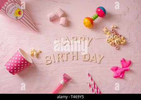 Festa di compleanno sfondo, il bordo dei confetti, caramelle, lecca-lecca e dono sulla superficie di rosa, copia spazio, vista dall'alto Foto Stock