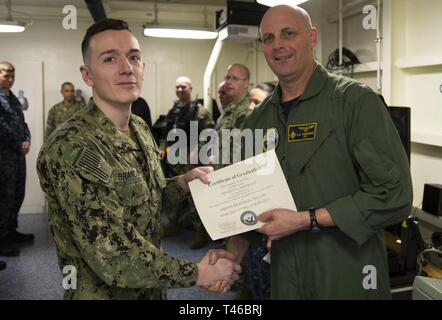 NEWPORT NEWS, Va. (11 marzo 2019) Capt. John J. Cummings, USS Gerald Ford (CVN 78) comandante, presenta la marina militare delle forze di sicurezza Sentry Certificato di diploma di Airman Dillon Brandon, da Philadelphia, assegnato a Ford del dipartimento dell'aria durante un in-port security force (ISF) Classe di laurea. Ford è attualmente in fase di post-shakedown disponibilità presso Huntington Ingalls Industries-Newport News la costruzione navale. Foto Stock