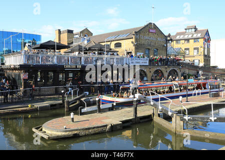 Barge con turisti di passaggio attraverso il Camden Lock sul Regents Canal, nel sole primaverile, a nord di Londra, Regno Unito Foto Stock