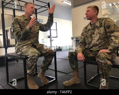 Lt. Col. Derek Baird, sinistra, 3-16 Campo reggimento di artiglieria, gesti durante un'intervista mentre suo fratello il comando Sgt. Il Mag. Thomas Baird, destra, 504th MI BDE ex CSM, ascolta, Marzo 8, 2019, Fort Hood, Texas. Entrambi i gemelli sono identici che servono lo stesso post. Foto Stock