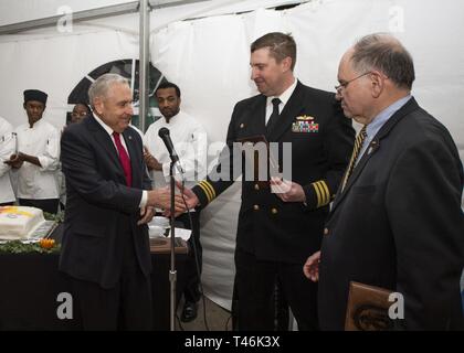 BOSTON (14 marzo 2019) della Cmdr. Morgan Roberts, comandante della Arleigh Burke-class guidato-missile destroyer USS Jason Dunham (DDG 109), scambi placche con il cap. Tom Hennessey (Ret.), a sinistra, e il Sig. Stephen Schnitzer, Massachusetts Bay consiglio della Lega Navale degli Stati Uniti i rappresentanti, durante un ricevimento a bordo della nave. Dunham è a Boston per partecipare nella città del San Patrizio eventi. Foto Stock