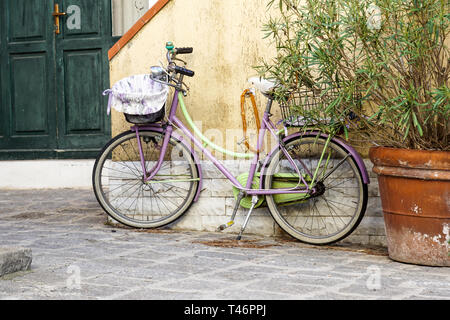 Una donna di bicicletta è legato ad un palo di ferro. Nelle vicinanze vi è la cornice rossa di un sito in costruzione. Foto Stock