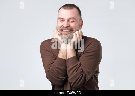 Felice uomo maturo con barba tenere le braccia vicino al mento. Foto Stock