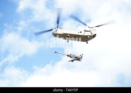 Uno dei sei Chinooks, elicotteri CH-47, arriva con la M77 Obice durante il campo artiglieria, 2d della Cavalleria artiglieria batteria raid aereo in Grafenwoehr Area Formazione, Germania, 12 marzo 2019. Colpire le gamme di 30.000km 32,000km, M77 Obice fornisce potenza di fuoco al bersaglio avversari in lontano distanze. Foto Stock