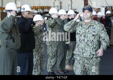 NEWPORT NEWS, Va. (14 marzo 2019) Chief Warrant Officer Brad Alston, da Atmore, Alabama, assegnato alla USS Gerald Ford CVN (78) intermedio di aeromobili al reparto manutenzione, restituisce la saluta di ufficiali come egli è rediretto a terra. Ford è attualmente in fase di post-shakedown disponibilità presso Huntington Ingalls Industries-Newport News la costruzione navale. Foto Stock