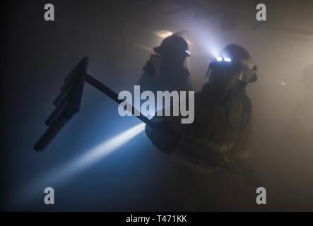 Inghilterra (14 marzo 2019) Danni Controlman Fireman James Moore utilizza un rastrello durante la revisione di un incendio simulato a bordo del Arleigh Burke-class guidato-missile destroyer USS Porter (DDG 78) a sostegno di bandiera ufficiale di formazione del mare in Plymouth, Inghilterra, 14 marzo 2019. Porter, distribuita a Rota, Spagna, è sulla sua sesta patrol NEGLI STATI UNITI Sesta flotta area di operazioni a sostegno degli Stati Uniti gli interessi di sicurezza nazionali in Europa e in Africa. Foto Stock