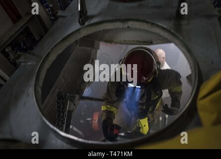 Inghilterra (14 marzo 2019) Danni Controlman Fireman James Moore si arrampica su un ladderwell per evacuare uno spazio dopo la lotta contro un incendio simulato a bordo del Arleigh Burke-class guidato-missile destroyer USS Porter (DDG 78) a sostegno di bandiera ufficiale di formazione del mare in Plymouth, Inghilterra, 14 marzo 2019. Porter, distribuita a Rota, Spagna, è sulla sua sesta patrol NEGLI STATI UNITI Sesta flotta area di operazioni a sostegno degli Stati Uniti gli interessi di sicurezza nazionali in Europa e in Africa. Foto Stock