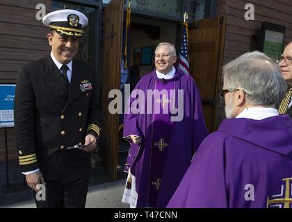 BOSTON (14 marzo 2019) della Cmdr. Steven Puskas, delegato della Arleigh Burke-class guidato-missile destroyer USS Jason Dunham (DDG 109), parla con il Rev. James Flavin e altri dopo di che frequentano la Messa al Santuario di Nostra Signora del Buon Viaggio nel sud di Boston. La Dunham è a Boston per partecipare nel centro storico della città di San Patrizio eventi. Foto Stock